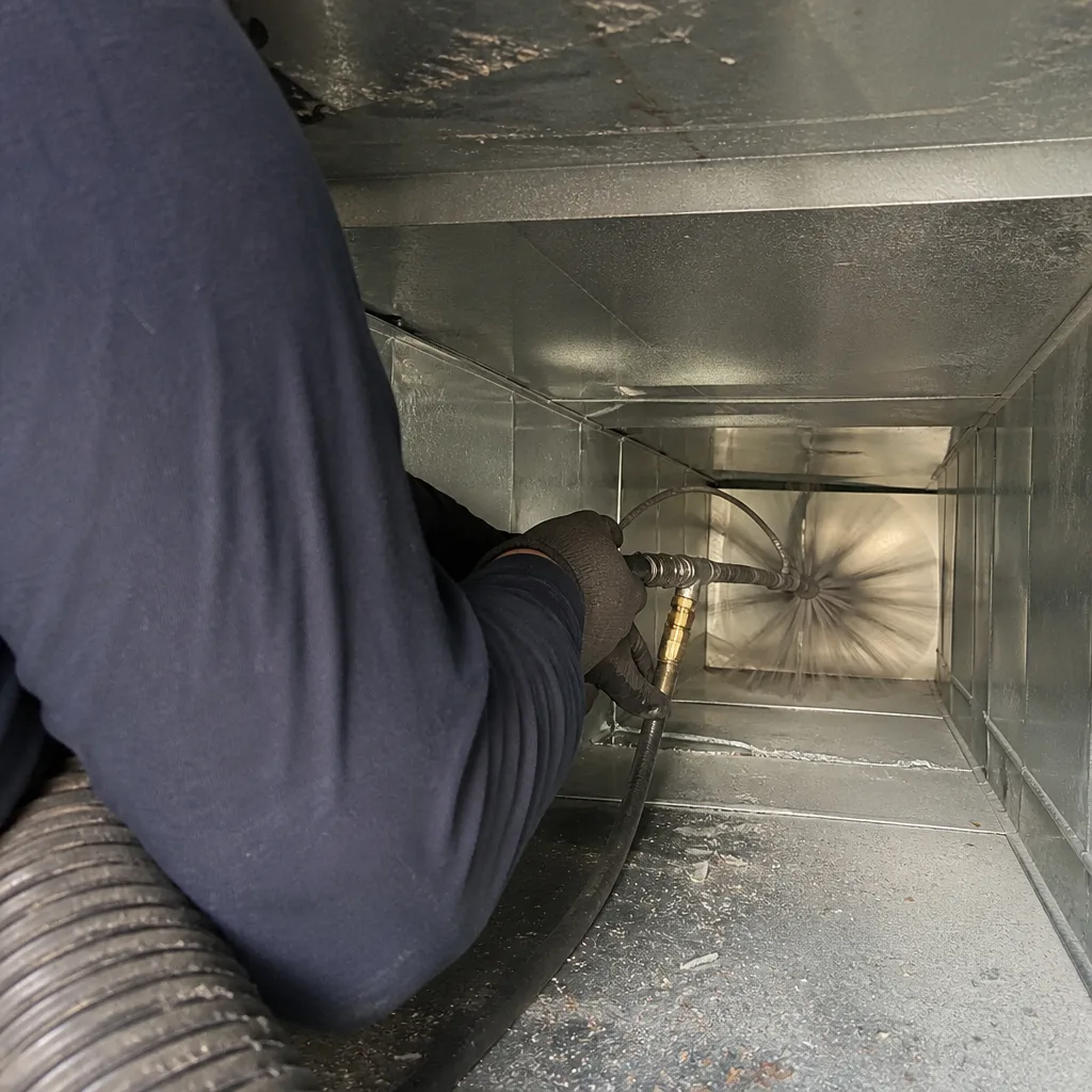 Technician using a rotating brush tool to clean interior air ducts